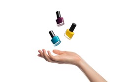 Nail polish bottles levitate, flying over a woman's hand