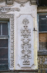 Fragment of the facade of an old house. Elements of the architectural decor of the building. Architectural stucco detail.