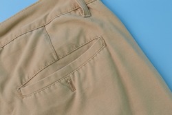 Close up view of a man's pant pocket isolated on a blue background