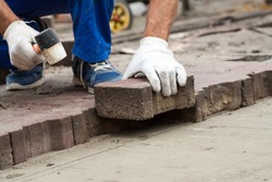 professional  Workers  Laying Paving Slabs by mosaic close-up in blue overalls