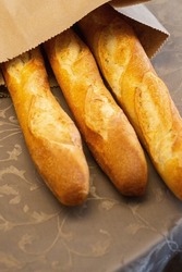 Three fresh french traditional baguette bread in a paper sack inside a fancy house