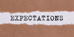 Expectations word written behind torn paper.