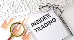 INSIDER TRADING text written on notebook with keyboard, chart,and glasses