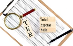 TER TOTAL EXPENSE RATIO text on a wooden block on chart background
