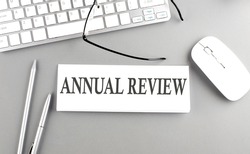 ANNUAL REVIEW text on a paper with keyboard on grey background