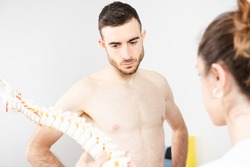 Shirtless athletic patient paying attention of the explanation of a physiotherapist