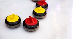 Granite stones with a red and yellow  handles on ice for curling on ice. olympic game sport