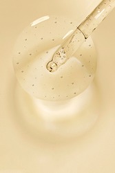 Liquid serum and dropper on a beige  background top view. Serum drops in the form of a circle with a pipette.
