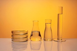 Medical or chemical background with laboratory equipment and liquids. On an orange background, front view.