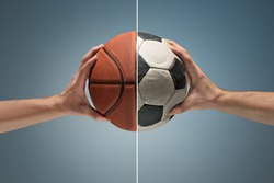 Hands holding soccer and basketball balls on gray studio background. concept of confrontation, differences in taste and preference