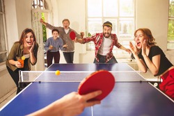 Group of happy young friends playing ping pong table tennis at office or any room. Concept of healthy sport and genuine emotions. Lifestyle, rest concepts