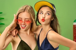 Cute girls in swimsuit posing at studio. Summer portrait caucasian teenagers on a green background. Concept of summer, summertime, recreation, break, vacation, travel.