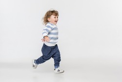 Portrait of happy joyful running beautiful little boy, studio shot on white