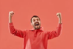 I won. Winning success happy man celebrating being a winner. Dynamic image of caucasian male model on coral studio background. Victory, delight concept. Human facial emotions concept. Trendy colors