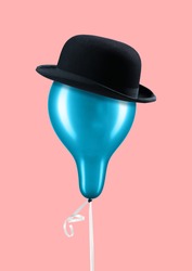 A light aristocrat. Blue balloon with black male hat and white tape against trendy coral background. Good manners in the air. Vintage style. Fashion concept. Modern design. Contemporary art collage.