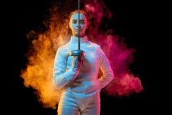 Historical time. Teen girl in fencing costume with sword in hand isolated on black background, neon lighted smoke. Practicing and training in motion, action. Copyspace. Sport, youth, healthy lifestyle