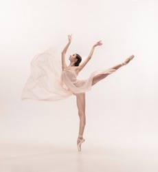 Graceful classic ballerina dancing, posing isolated on white studio background. Tender peach cloth. The grace, artist, movement, action and motion concept. Looks weightless, flexible. Fashion, style.