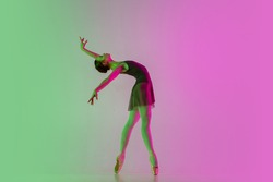 Inspired. Young and graceful ballet dancer isolated on gradient pink-green studio background in neon. Art, motion, action, flexibility, inspiration concept. Flexible ballerina, weightless jumps.