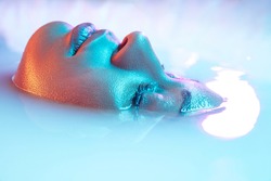 Cheeks. Beautiful female face in the milk bath with soft glowing in blue-pink neon light. Copyspace for advertising. Modern neoned colors, foam. Beauty, fashion, style, skincare concept. Attractive.