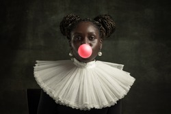 Bubbles gum. Medieval African young woman in black vintage dress with big white collar isolated on dark green background. Concept of comparison of eras, modernity and renaissance. White pearls