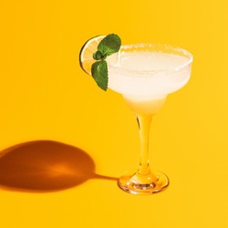 Sweet and sour. Margarita glass isolated on bright yellow neon background with shadow. Close-up. Complementary colors, white, blue and yellow. Copy space for ad. Pop art