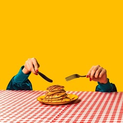 Breakfast. Food pop art photography. Female hand and sweet pancakes on plaid tablecloth isolated on bright yellow background. Vintage, retro 80s, 70s style. Complementary colors, Copy space for ad