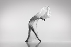 Liberty. Black and white portrait of graceful ballerina dancing with fabric, cloth isolated on grey studio background. Grace, art, beauty, contemp dance concept. Weightless, flexible actress