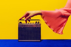 Tune, Old radio. Female hand touching radior, wireless isolated on bright blue and yellow background. Vintage, retro 80s, 70s style. Complementary colors. Concept of fashion, art, creativity, ad