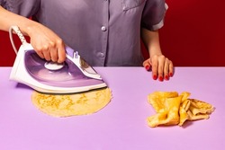 Pop art photography. Creative portrait of girl ironing pancakes on lilac color tablecloth. Vintage, retro 80s, 70s style. Complementary colors, Copy space for ad, text