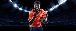 Winner emotions.Excited professional soccer, football player in football kit standing with ball and shouting over dark night stadium with flashlights background. Sport, competition, championship, wow