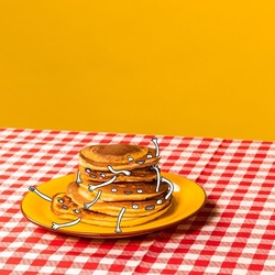 Funny breakfast. Food pop art photography. Plate with pancakes with funny drawings on plaid tablecloth isolated on bright yellow background. Cartoon, vintage, retro style. Copy space for ad, text