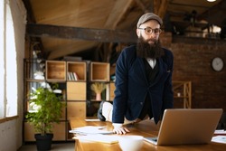 Unusual business process. Young bearded man, office clerk having fun, doing yoga on wooden table in modern office at work time with gadgets. Concept of business, healthy lifestyle, sport, hobby