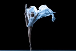 Freedom. Graceful classic ballerina dancing with weightless cloth isolated on black studio background. Theater, art, beauty, grace, action and motion, ad concept. Artist of ballet in solo performance