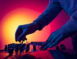 Close-up image of male hands, dj making sounds at night club party with professional sound mixer. Modern party style. Deep beats. Concept of music, fun, youth culture, enjoyment, lifestyle