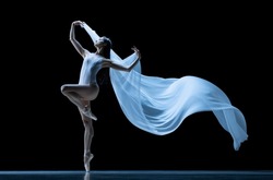 Beauty. Graceful classic ballerina dancing with weightless cloth isolated on black studio background. Theater, art, grace, action and motion, ad concept. Artist of ballet in solo performance