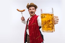 Happy man wearing traditional fest Bavarian or German outfit with big beer glass and fried sausage celebrating Oktoberfest. Alcohol, traditions, holidays, taste concept. Copy space for ad