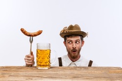 Wow. Happy man wearing traditional fest Bavarian or German outfit with big beer glass and fried sausage celebrating Oktoberfest. Alcohol, traditions, holidays, taste concept. Copy space for ad