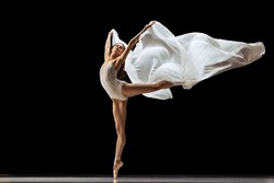 Beauty. Graceful classic ballerina dancing with weightless cloth isolated on black studio background. Theater, art, grace, action and motion, ad concept. Artist of ballet in solo performance