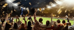 Back view of football, soccer fans cheering their team, holding flag at crowded stadium at evening time. Concept of sport, cup, world, team, event, competition, hobby, lifestyle, emotions