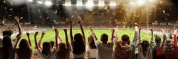 Back view of football, soccer fans emotionally cheering their team at crowded stadium at evening time. Hobby of millions of people. Concept of sport, cup, world, team, event, competition