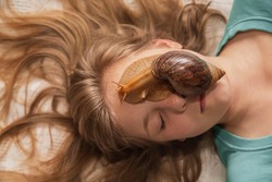Young woman receiving snail facial massage. Cleaning procedure in spa salon.