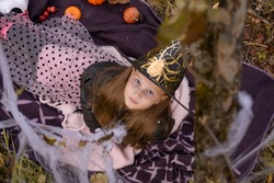 Funny baby girl in a witch costume for Halloween is sitting on the ground and looking up, top view. Happy Halloween.