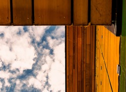 Abstract image of a blue sky with clouds, wooden yellow roof and wall
