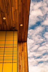 Image of a blue sky with clouds and a wooden yellow roof and wall with lights