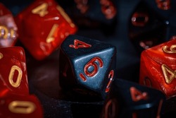 A close-up image of a black 10-sided die with red numbers