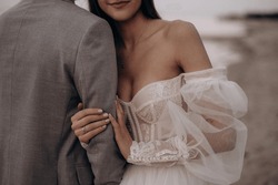 Close up of bride with ring hugging groom at beach, seaside. Woman wearing wedding dress smiling, getting married with man wearing costume. Concept of marriage and family relations.