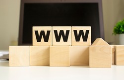 The word WWW is written on wooden cubes lying on the office table in front of a laptop.