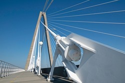 Low-angle photo of Arthur Ravenel Jr. Bridge, showing a cable anchorage in the foreground, also cable stays, the tower, and the pedestrian walkway of the deck.