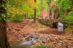 Autumn scene of stone building with water mill wheel  with stone steps leading to silky effect stream through rocks