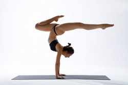 Strong handstand. Athletic slim woman. Yoga pose. White studio background. Asana.